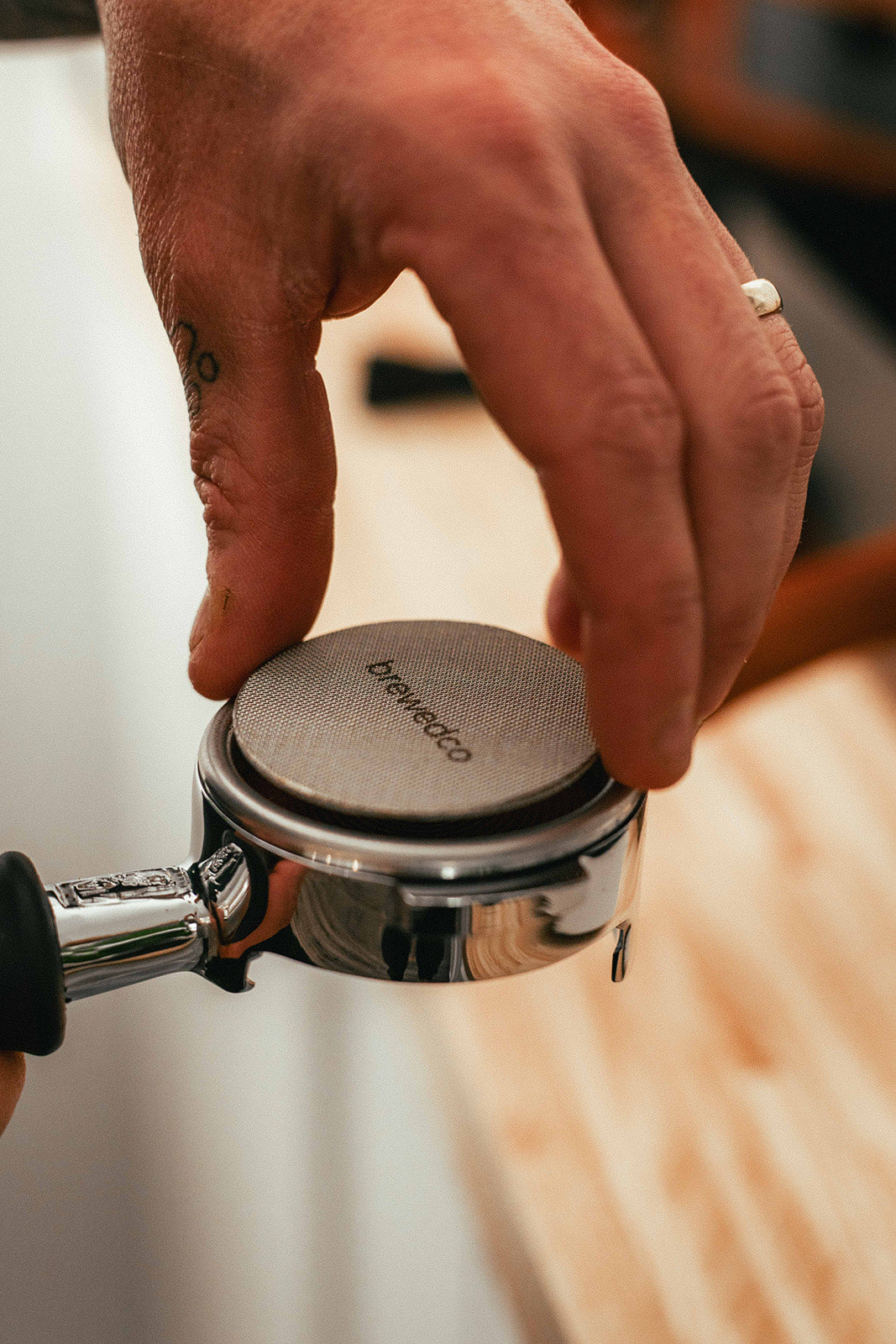 Coffee Puck Screen in Bottomless Portafilter being Tamped by Coffee Tamper